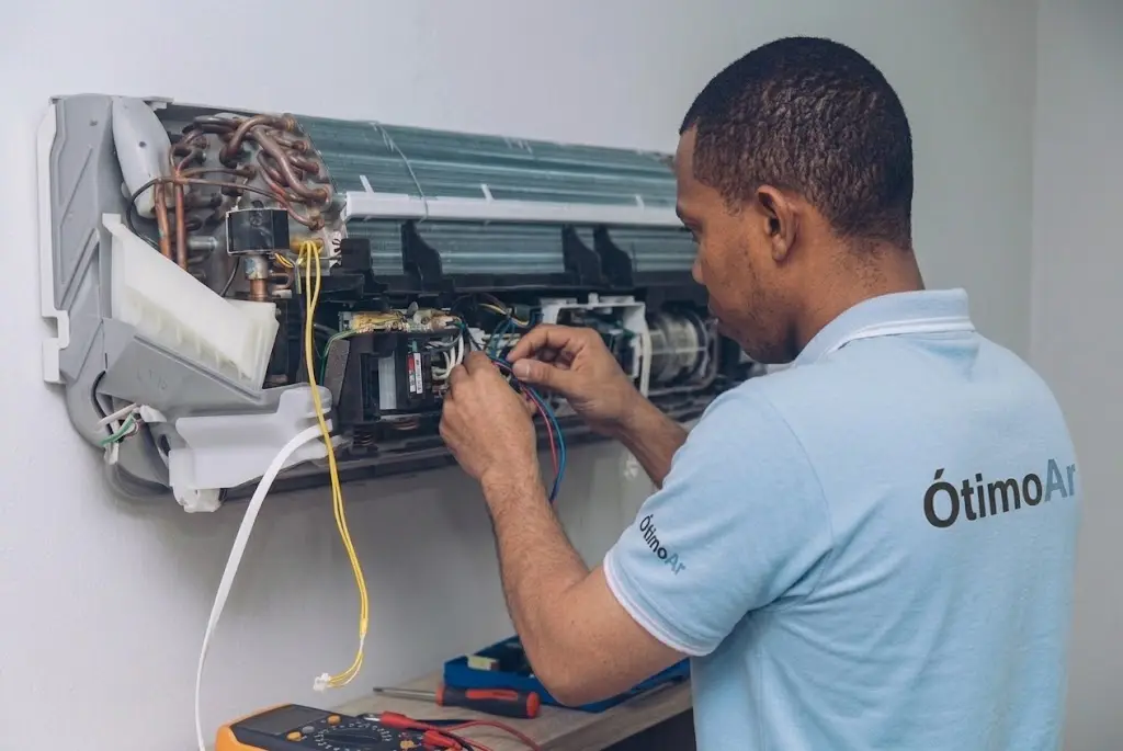 Técnico da Ótimo Ar fazendo diagnóstico elétrico em ar-condicionado aberto